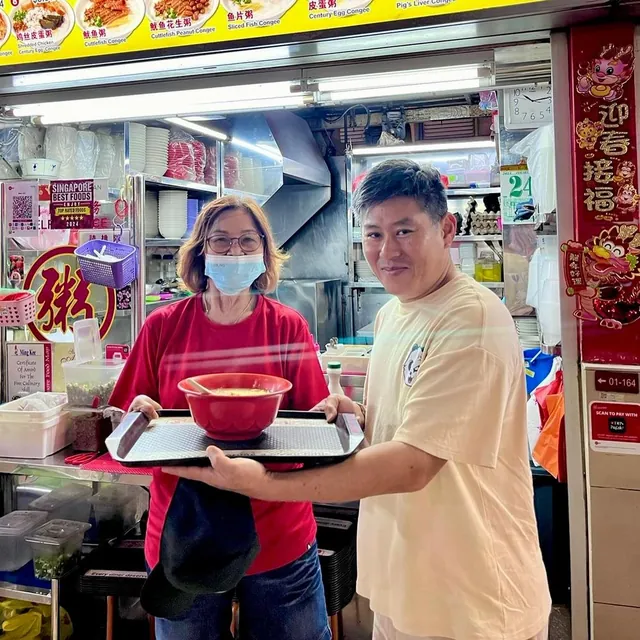 Ming Kee's owner handing over a bowl of porridge at the counter